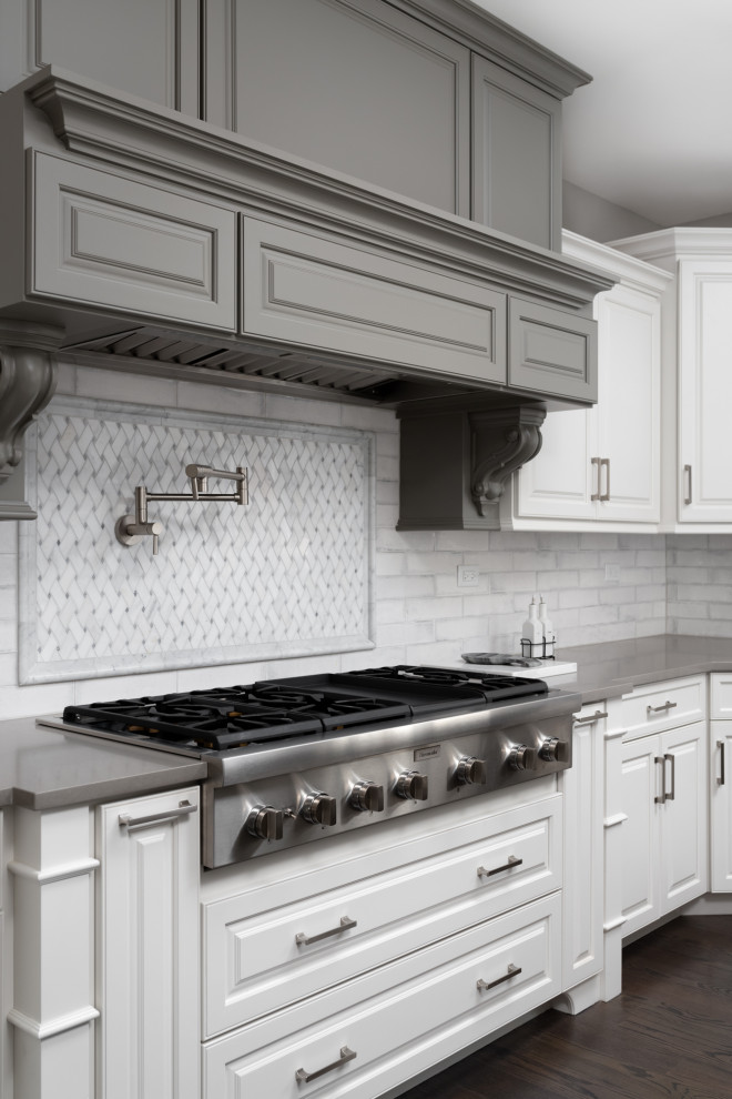 Immagine di una cucina design con ante bianche, paraspruzzi bianco, elettrodomestici in acciaio inossidabile e top grigio