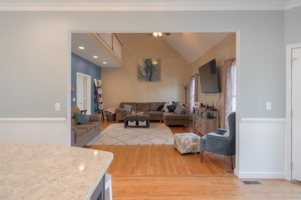 Example of a mid-sized transitional galley medium tone wood floor eat-in kitchen design with an undermount sink, flat-panel cabinets, white cabinets, quartz countertops, white backsplash, subway tile backsplash, stainless steel appliances, an island and white countertops