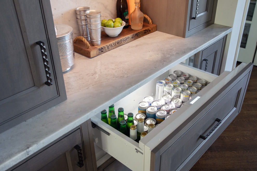 Small eclectic galley home bar in Milwaukee with no sink, beaded inset cabinets, grey cabinets, quartzite benchtops, white splashback, stone slab splashback, dark hardwood floors, brown floor and white benchtop.