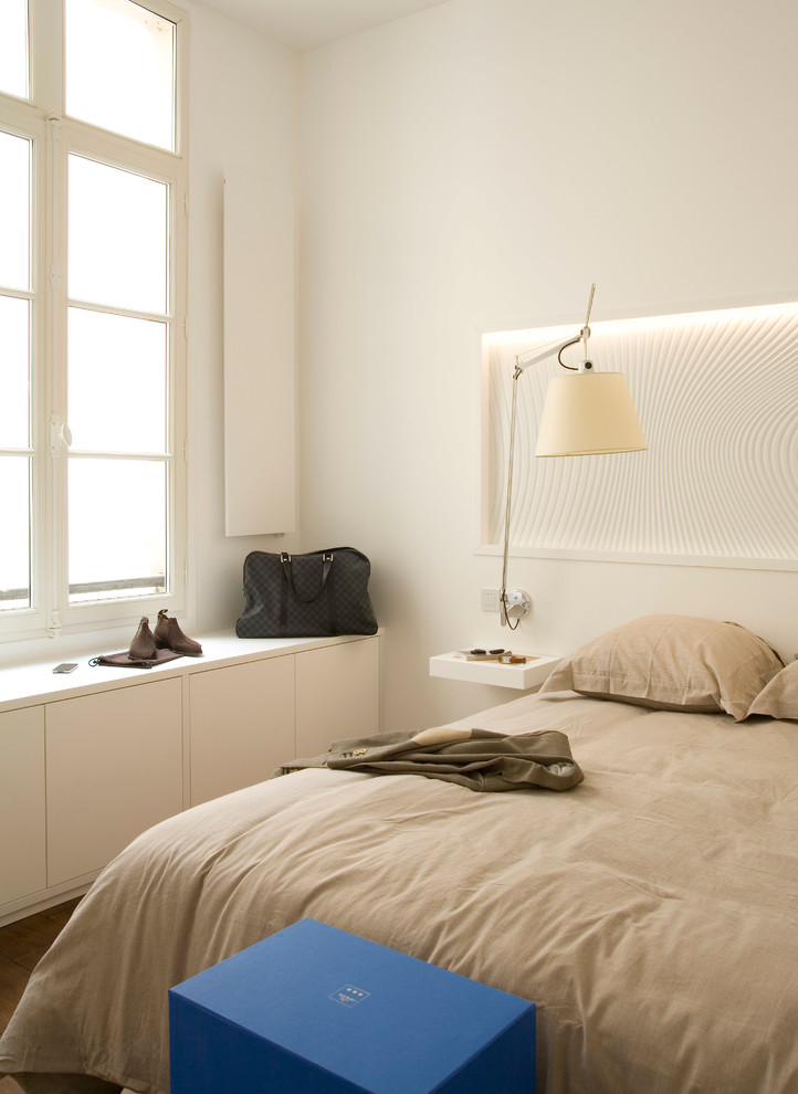 This is an example of a contemporary bedroom in Paris with white walls and medium hardwood floors.