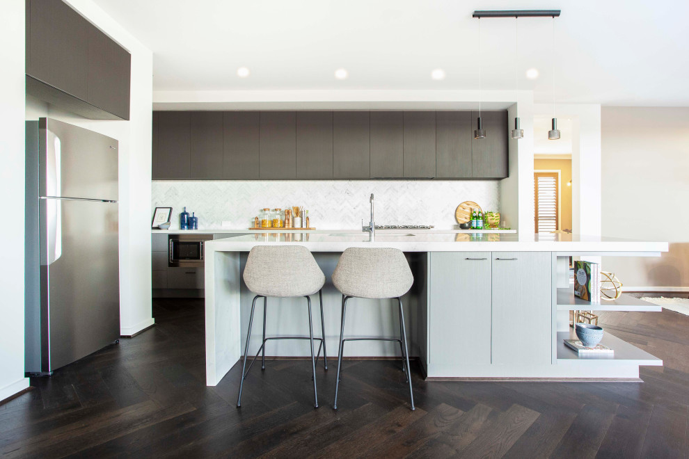 Contemporary l-shaped kitchen in Melbourne with an undermount sink, dark wood cabinets, quartz benchtops, white splashback, ceramic splashback, painted wood floors, with island, brown floor and white benchtop.
