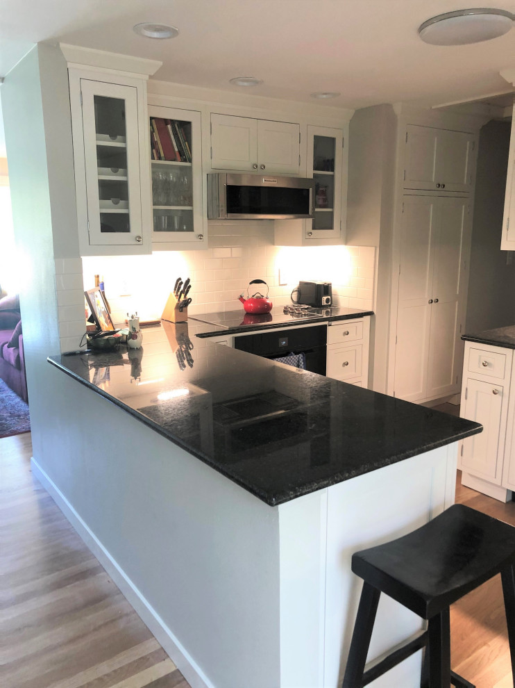 Mid-sized transitional eat-in kitchen in Seattle with beaded inset cabinets, white cabinets, quartz benchtops, light hardwood floors, a peninsula and black benchtop.