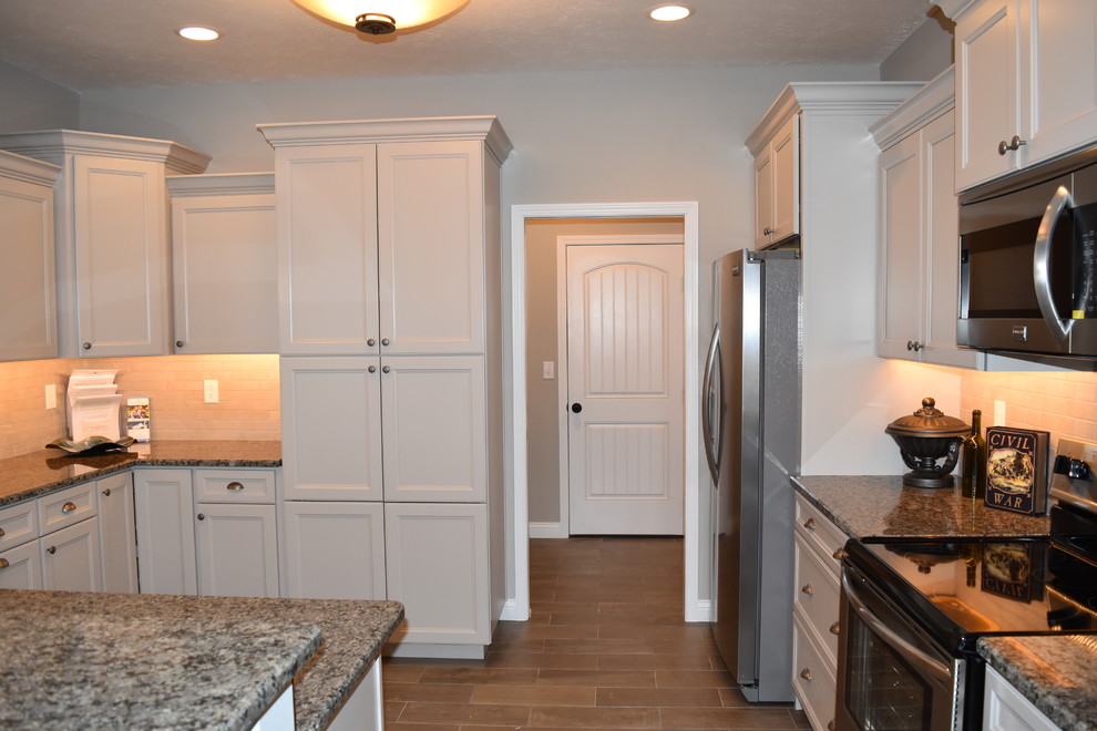 Inspiration for a mid-sized transitional u-shaped porcelain tile enclosed kitchen remodel with an undermount sink, recessed-panel cabinets, beige cabinets, granite countertops, beige backsplash, subway tile backsplash, stainless steel appliances and a peninsula