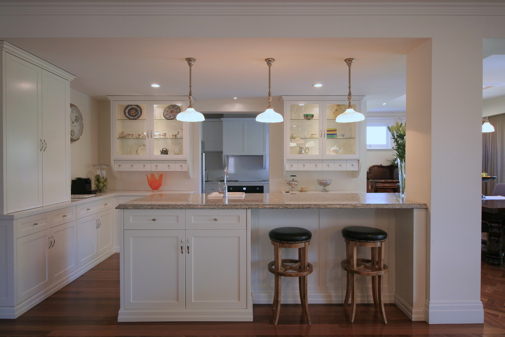 Arts and crafts open plan kitchen in Melbourne with shaker cabinets, white cabinets, marble benchtops, medium hardwood floors, with island and brown benchtop.