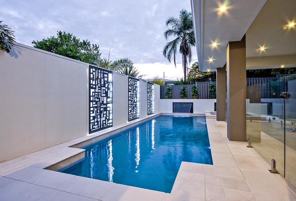 Small modern courtyard custom-shaped lap pool in Brisbane with a water feature and natural stone pavers.