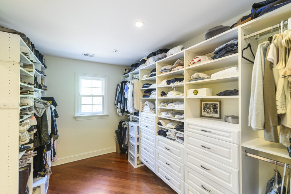 Photo of a large traditional walk-in wardrobe in DC Metro with white cabinets, dark hardwood floors and red floor.