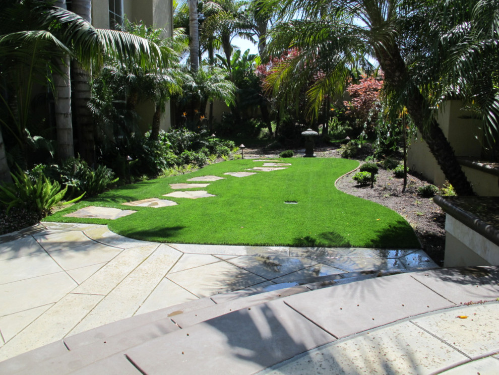 Inspiration for a mid-sized tropical backyard garden in Los Angeles with a garden path and natural stone pavers.