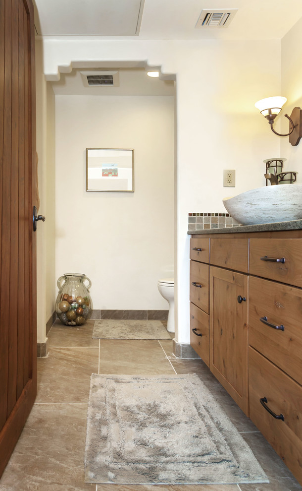 Design ideas for a country powder room in Phoenix with recessed-panel cabinets, medium wood cabinets, brown tile, ceramic tile, beige walls, a vessel sink and granite benchtops.