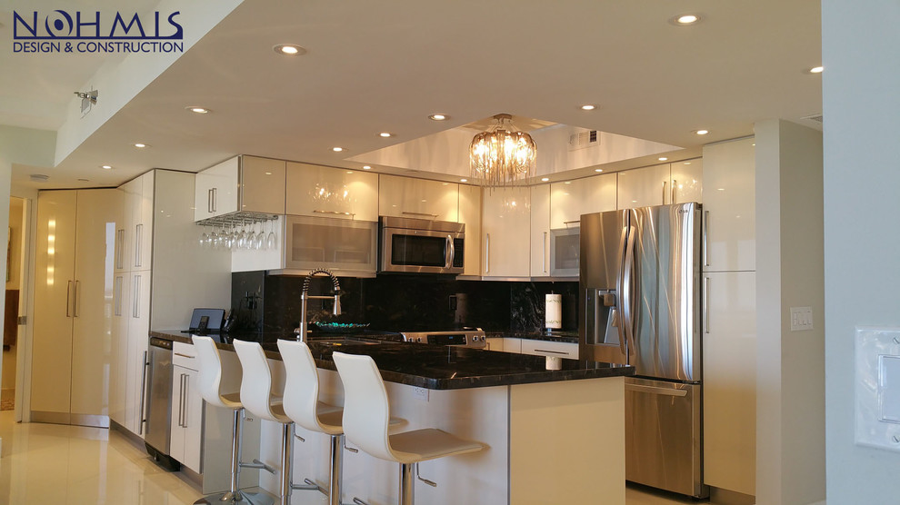 Photo of a small contemporary galley eat-in kitchen in Miami with a double-bowl sink, beaded inset cabinets, beige cabinets, granite benchtops, beige splashback, ceramic splashback, stainless steel appliances, marble floors and with island.