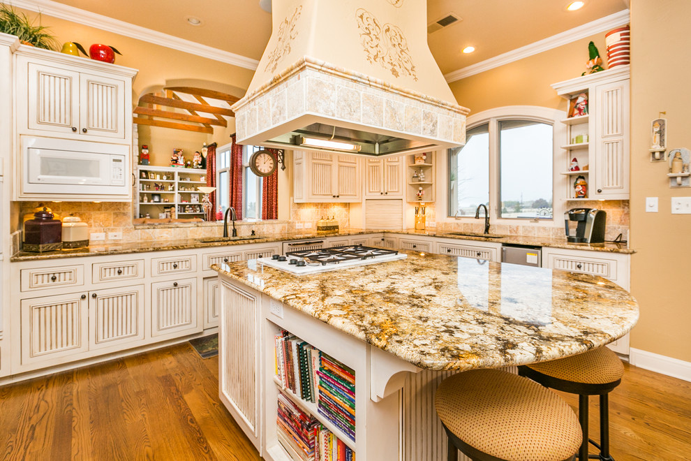 Large traditional u-shaped eat-in kitchen in Albuquerque with an undermount sink, white cabinets, granite benchtops, beige splashback, stone tile splashback, medium hardwood floors, with island, louvered cabinets and panelled appliances.