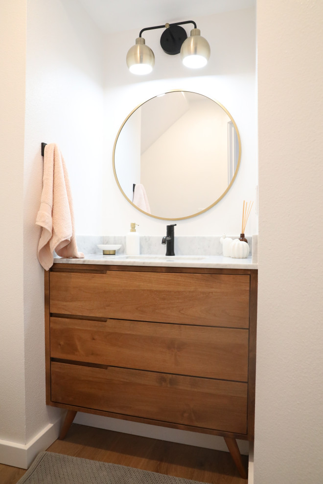 This is an example of a mid-sized midcentury 3/4 bathroom in San Francisco with furniture-like cabinets, medium wood cabinets, white walls, medium hardwood floors, an undermount sink, marble benchtops, brown floor and white benchtops.