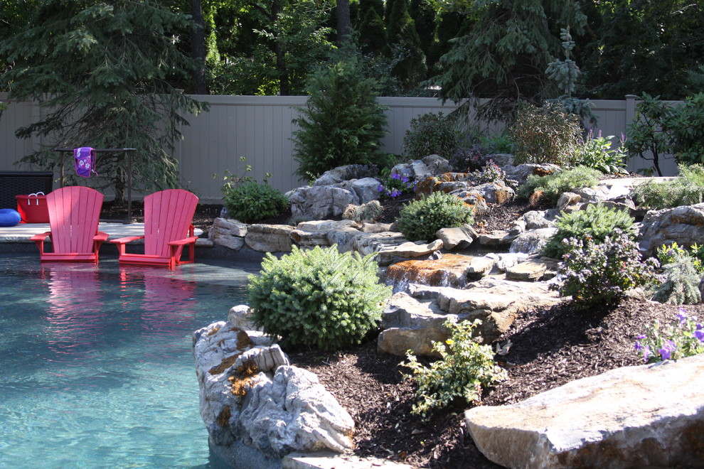 Photo of a large traditional backyard custom-shaped pool in New York with a water feature and concrete pavers.