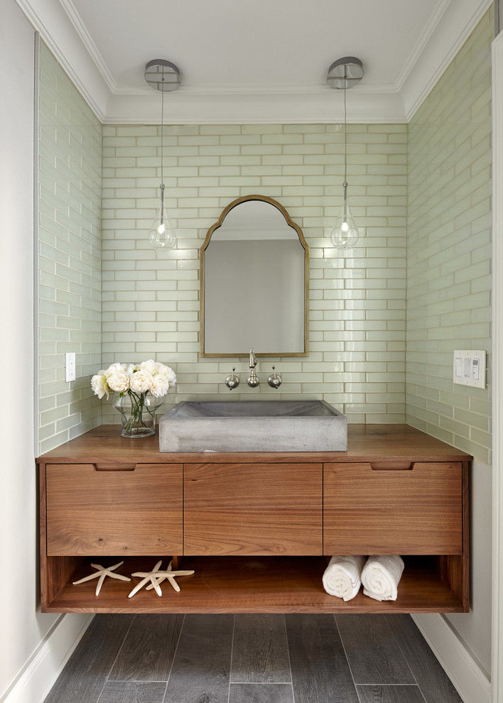 Design ideas for a beach style powder room in San Francisco with flat-panel cabinets, medium wood cabinets, green tile, subway tile, grey walls, a vessel sink, wood benchtops, grey floor and brown benchtops.