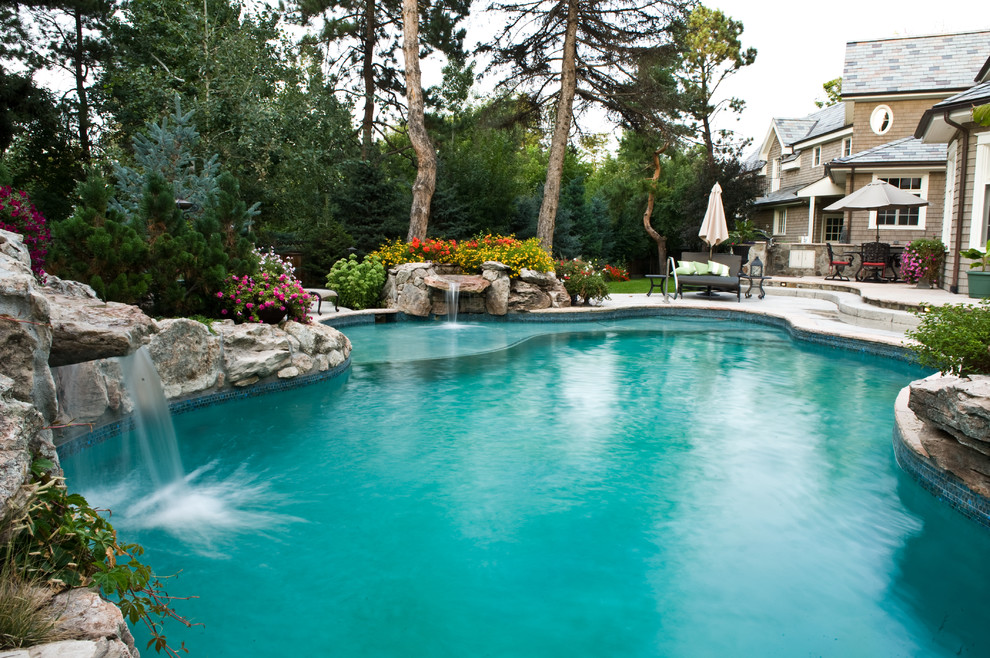 Photo of a large country backyard custom-shaped natural pool in Denver with a water feature and concrete pavers.