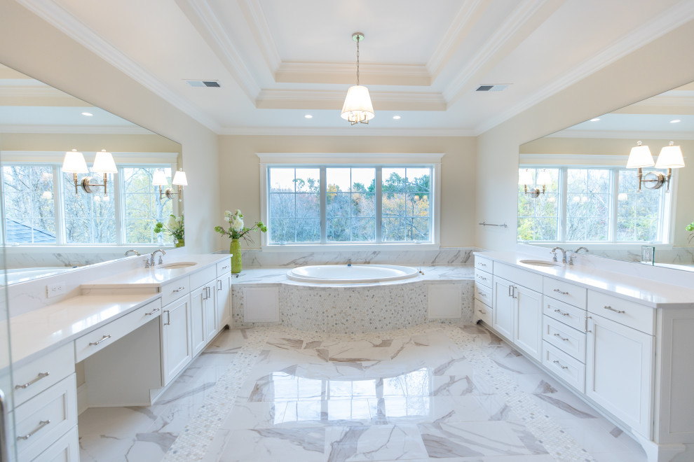 Large transitional master bathroom in DC Metro with recessed-panel cabinets, white cabinets, a drop-in tub, beige tile, stone tile, beige walls, porcelain floors, an undermount sink, engineered quartz benchtops, white floor, white benchtops, a double vanity, a built-in vanity and recessed.