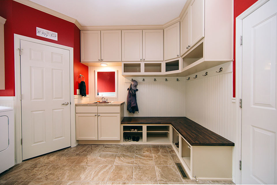 Inspiration for a mid-sized transitional u-shaped utility room in Other with a single-bowl sink, recessed-panel cabinets, white cabinets, red walls, porcelain floors, a side-by-side washer and dryer, brown floor and beige benchtop.