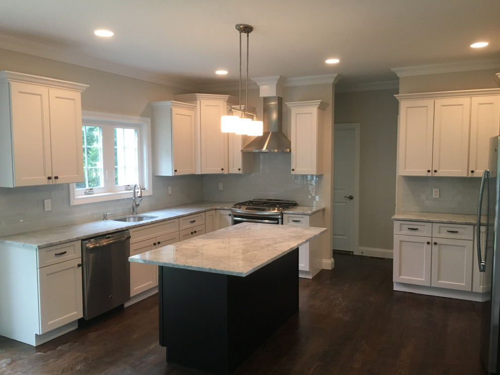 Exempel på ett mellanstort klassiskt vit vitt u-kök, med en undermonterad diskho, släta luckor, vita skåp, bänkskiva i kvarts, grått stänkskydd, stänkskydd i glaskakel, rostfria vitvaror, mörkt trägolv, en köksö och brunt golv