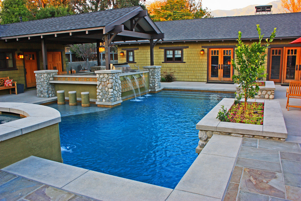 This is an example of a large arts and crafts backyard custom-shaped pool in Los Angeles with concrete pavers and a hot tub.
