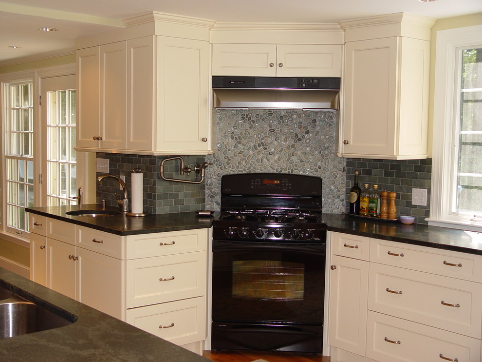 Example of a transitional kitchen design in Boston with an undermount sink, recessed-panel cabinets, white cabinets, granite countertops, black appliances and an island