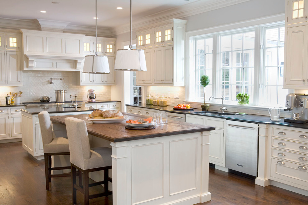 Design ideas for a large traditional kitchen in New York with an undermount sink, recessed-panel cabinets, white cabinets, white splashback, subway tile splashback, stainless steel appliances, medium hardwood floors, multiple islands and wood benchtops.