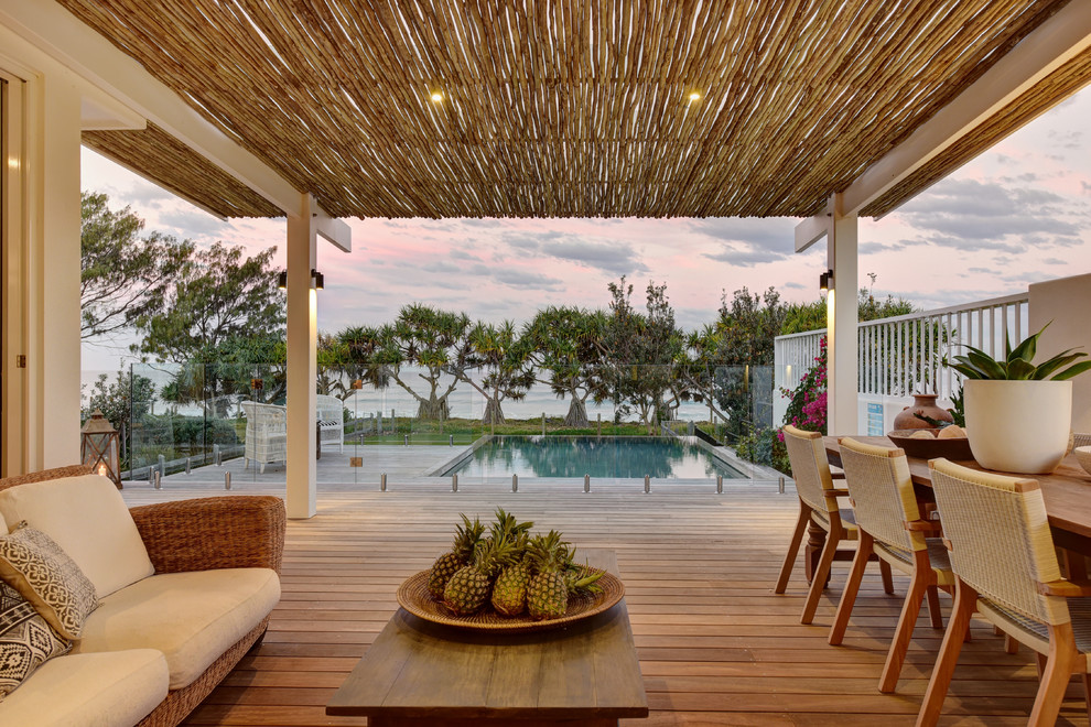 This is an example of a tropical backyard deck in Other with a pergola.
