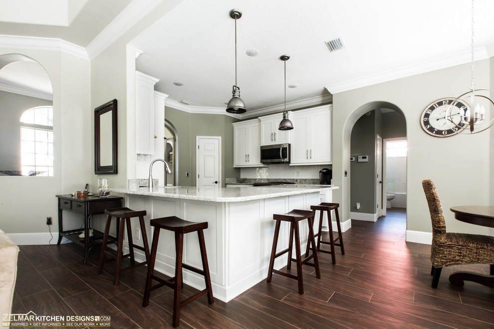 Design ideas for a mid-sized modern u-shaped open plan kitchen in Orlando with an undermount sink, shaker cabinets, white cabinets, quartz benchtops, white splashback, subway tile splashback, stainless steel appliances, porcelain floors and a peninsula.