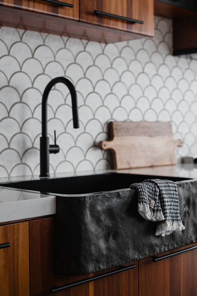 Inspiration for a transitional gray floor and tray ceiling kitchen remodel with a farmhouse sink, flat-panel cabinets, medium tone wood cabinets, white backsplash, stainless steel appliances, an island and white countertops