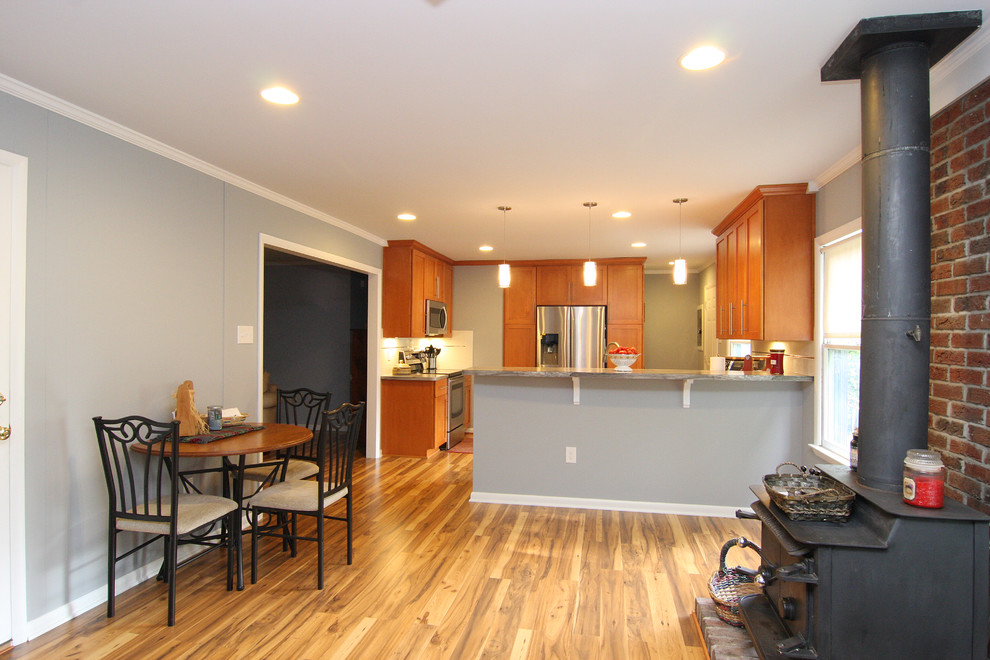 Example of a large transitional u-shaped medium tone wood floor eat-in kitchen design with a drop-in sink, recessed-panel cabinets, medium tone wood cabinets, laminate countertops, white backsplash, ceramic backsplash, stainless steel appliances and a peninsula