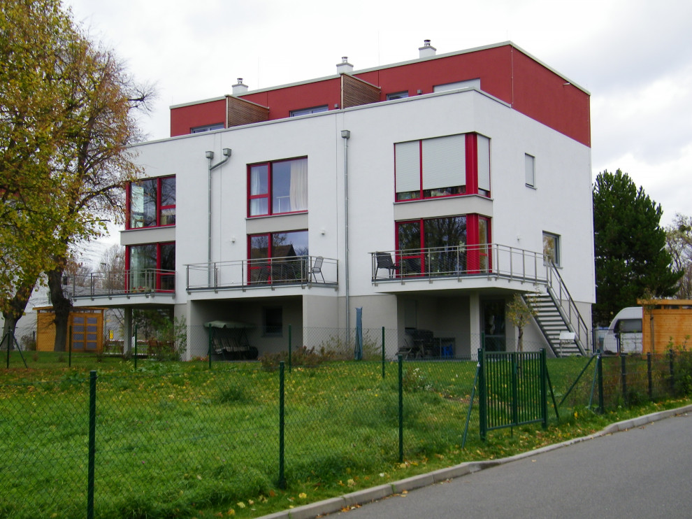 This is an example of an expansive contemporary split-level stucco townhouse exterior in Dresden with a flat roof and a mixed roof.