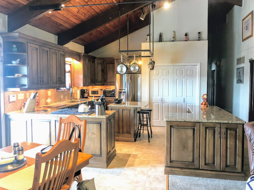 Photo of a large traditional l-shaped open plan kitchen in Baltimore with a single-bowl sink, raised-panel cabinets, brown cabinets, granite benchtops, beige splashback, ceramic splashback, stainless steel appliances, vinyl floors, multiple islands, beige floor and multi-coloured benchtop.