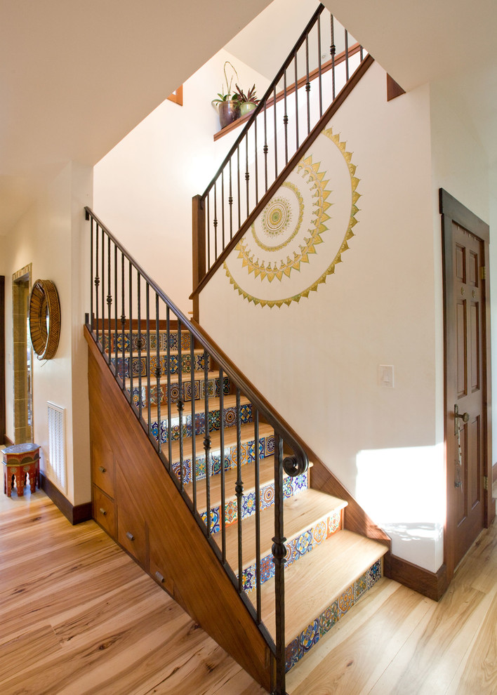 This is an example of an asian wood u-shaped staircase in San Francisco with tile risers and metal railing.