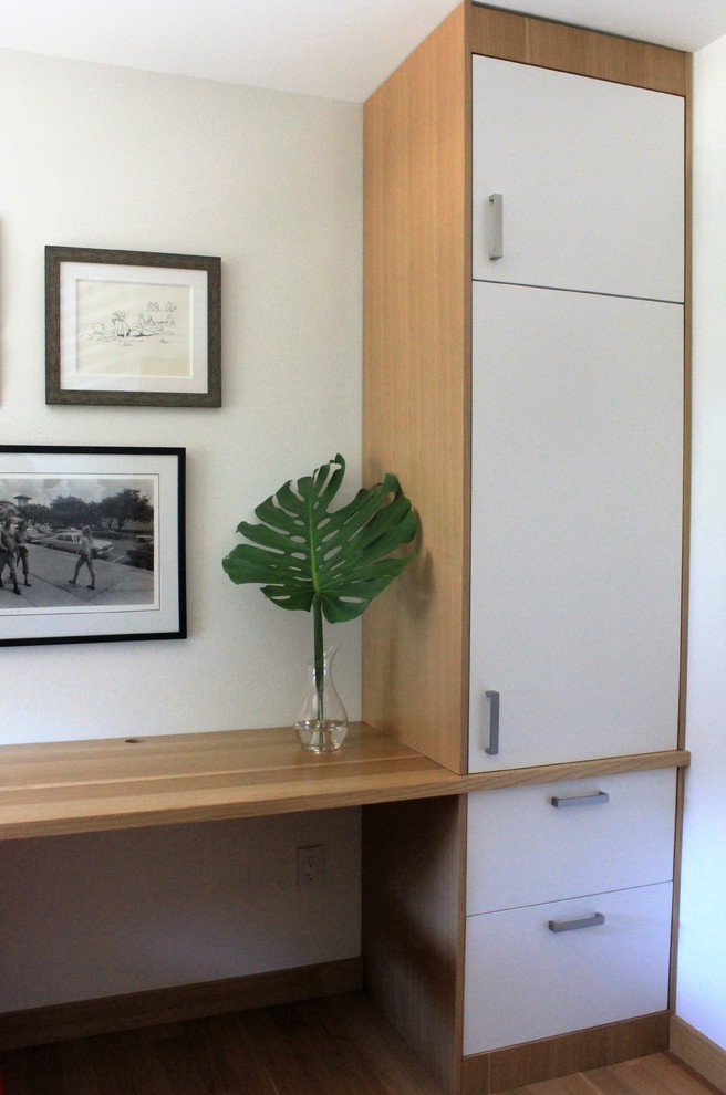 Mid-sized danish built-in desk light wood floor study room photo in Austin with white walls and no fireplace