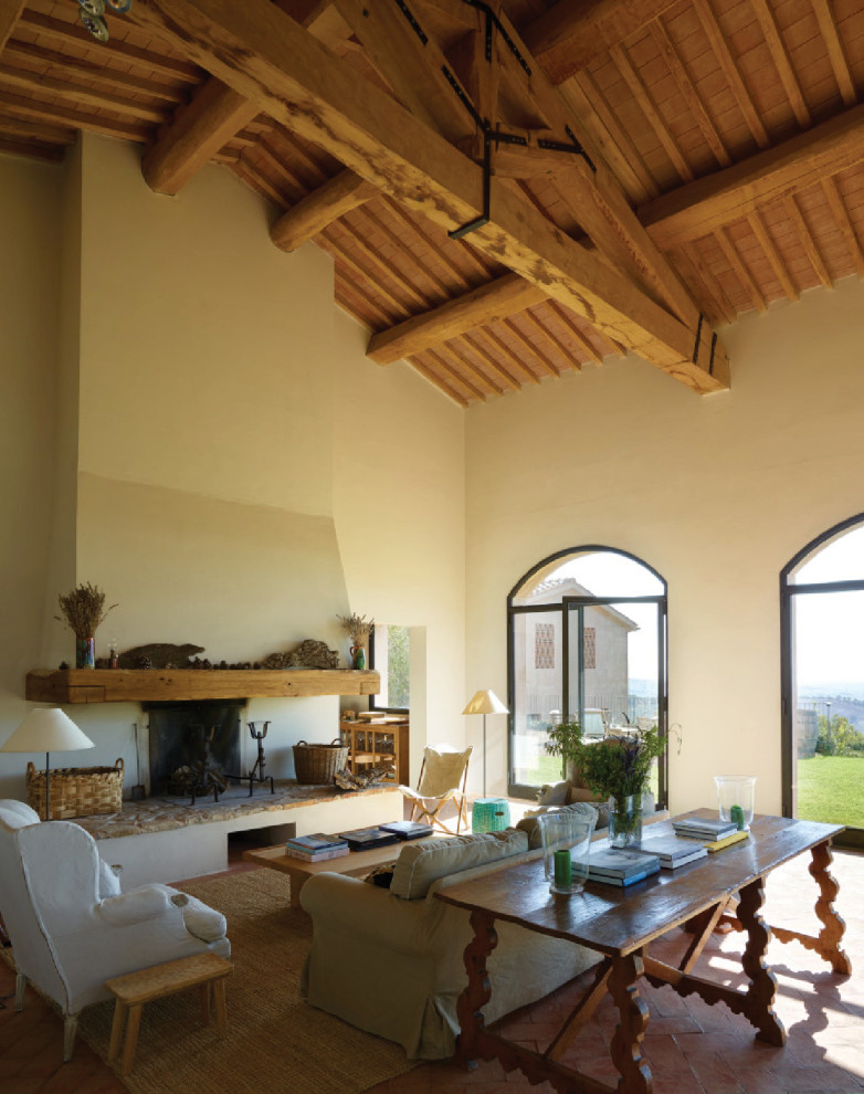 Mediterranes Wohnzimmer mit beiger Wandfarbe, Kamin, rotem Boden, freigelegten Dachbalken, gewölbter Decke, Holzdecke, Terrakottaboden und Kaminumrandung aus Holz in Rom