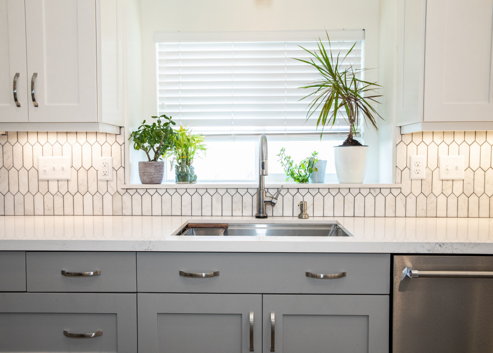 Example of a mid-sized trendy medium tone wood floor open concept kitchen design in Salt Lake City with an undermount sink, shaker cabinets, gray cabinets, quartzite countertops, white backsplash, mosaic tile backsplash, stainless steel appliances, an island and white countertops