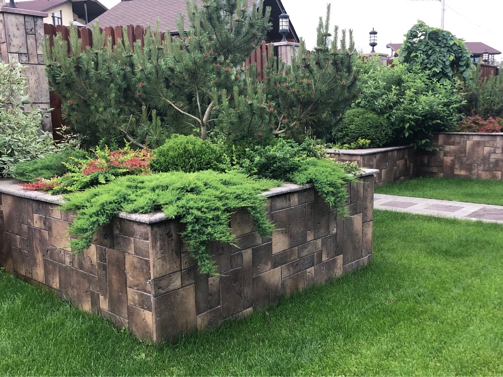 This is an example of a contemporary partial sun garden for summer in Moscow with a retaining wall.