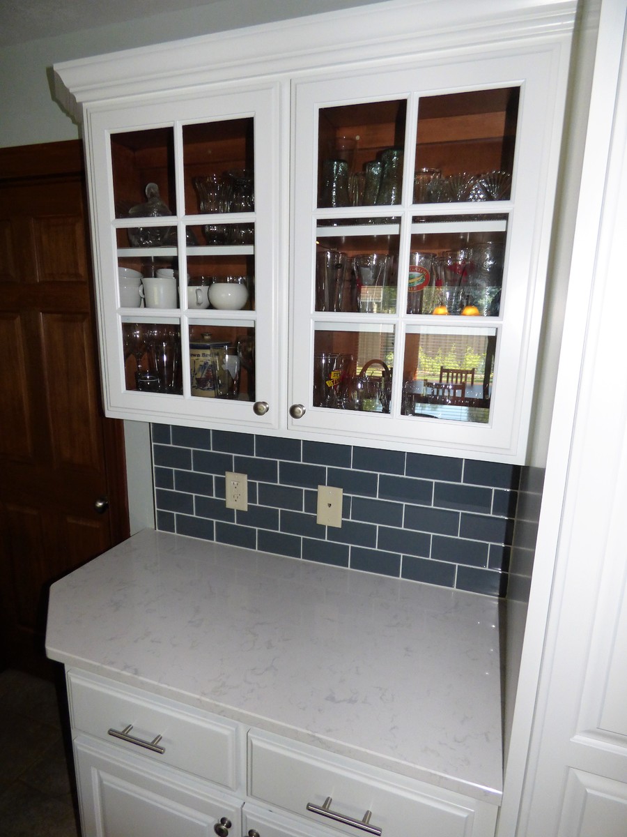 Inspiration for a mid-sized transitional l-shaped ceramic tile and gray floor eat-in kitchen remodel with an undermount sink, raised-panel cabinets, white cabinets, quartz countertops, blue backsplash, subway tile backsplash, stainless steel appliances and a peninsula