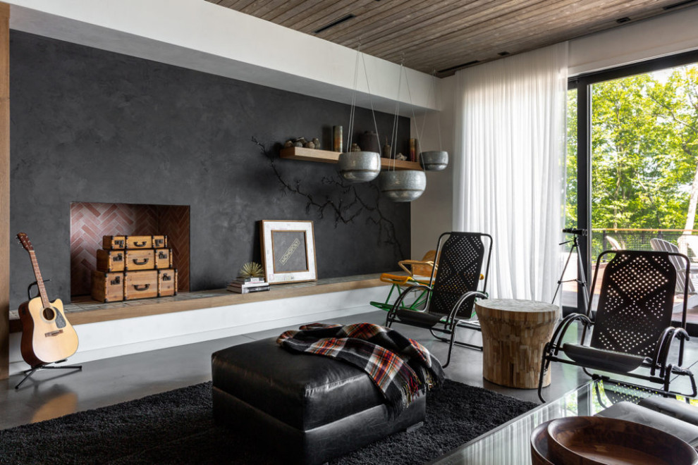 Mittelgroßes Uriges Wohnzimmer mit schwarzer Wandfarbe, Betonboden, Kamin, Kaminumrandung aus Backstein, grauem Boden und Holzdecke in Los Angeles