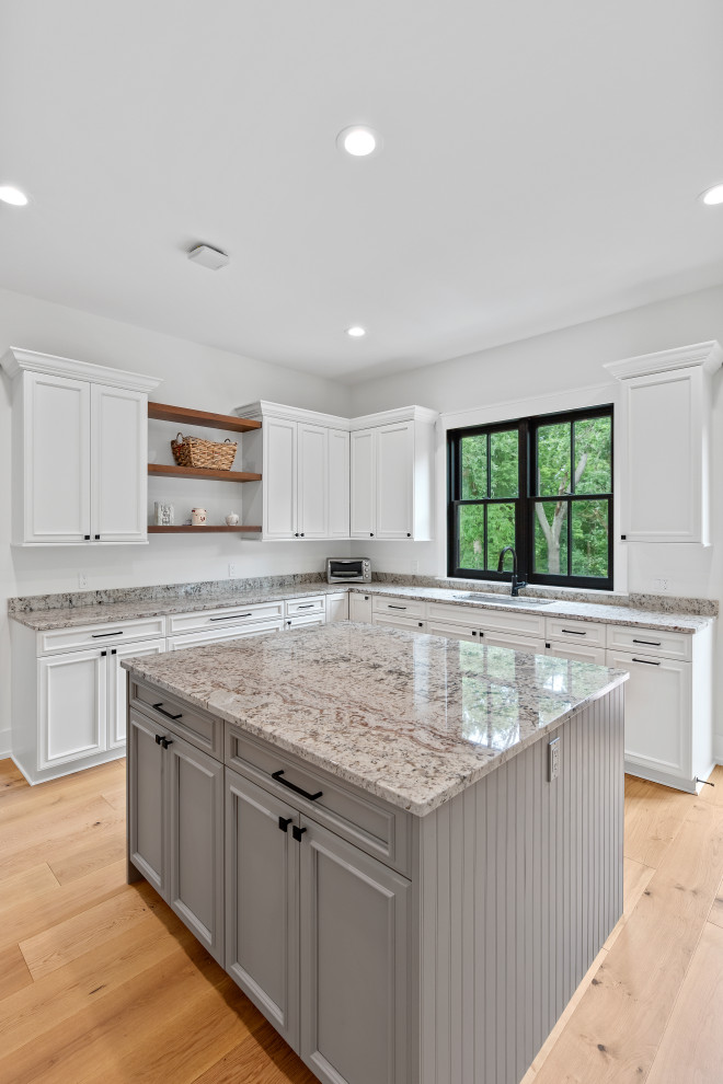 Design ideas for a large country l-shaped kitchen pantry in Milwaukee with an undermount sink, recessed-panel cabinets, white cabinets, granite benchtops, stainless steel appliances, light hardwood floors and with island.