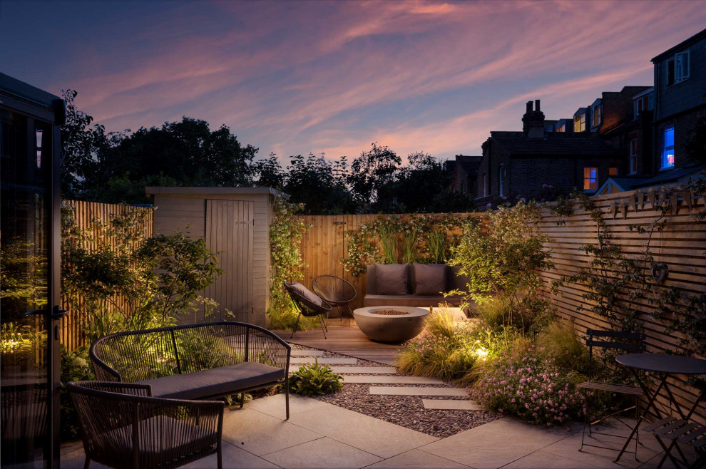Kleiner Moderner Garten hinter dem Haus mit Feuerstelle, Flusssteinen und Holzzaun in London