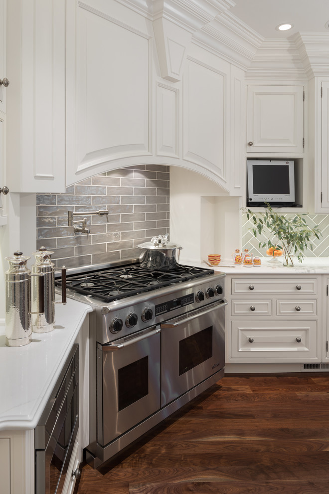 Inspiration for a huge transitional u-shaped medium tone wood floor and brown floor open concept kitchen remodel in Newark with a farmhouse sink, raised-panel cabinets, white cabinets, quartz countertops, gray backsplash, ceramic backsplash, white appliances, an island and white countertops