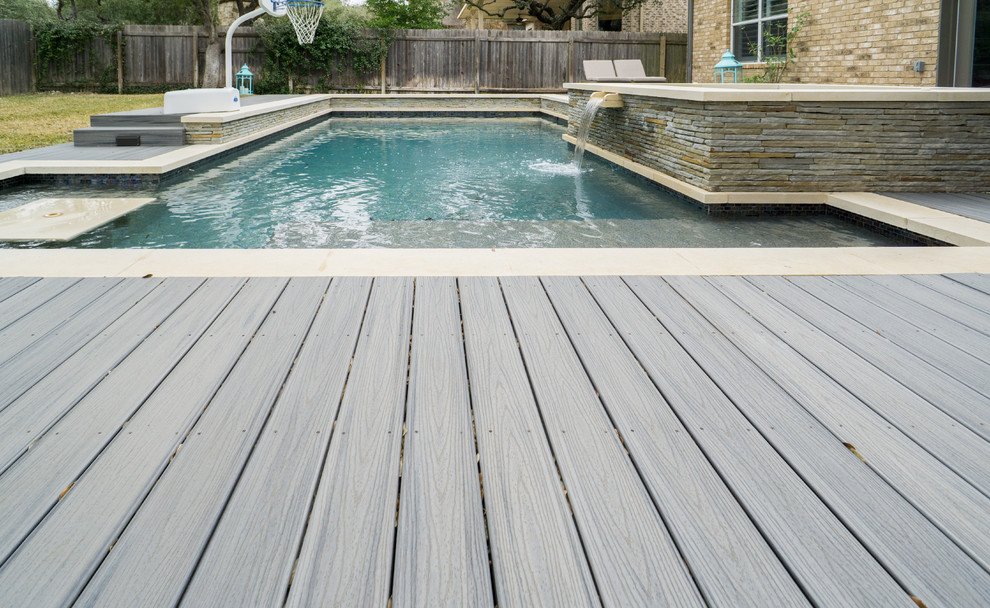 This is an example of a large contemporary backyard rectangular pool in Austin with a hot tub and decking.