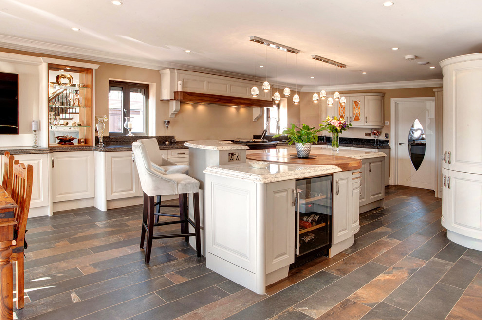 Large traditional eat-in kitchen in Other with an integrated sink, raised-panel cabinets, granite benchtops, black appliances, porcelain floors, with island, brown floor and multi-coloured benchtop.
