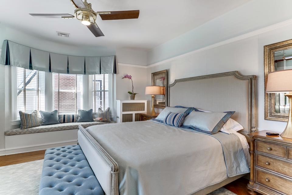 Large elegant master medium tone wood floor bedroom photo in New York with white walls