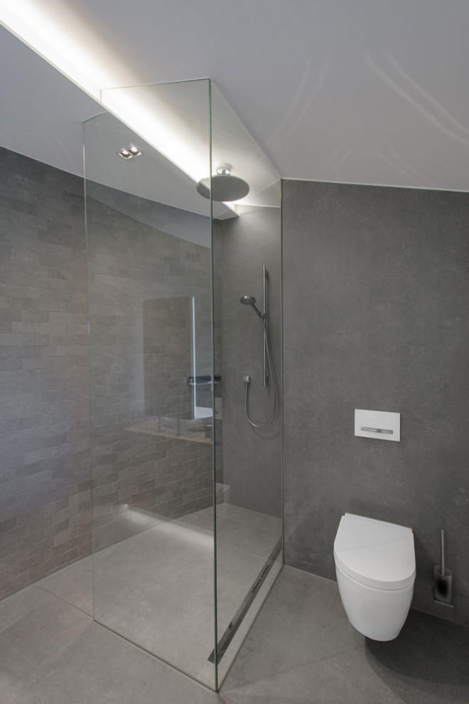 Design ideas for an industrial master bathroom in Dortmund with a curbless shower, a two-piece toilet, gray tile, ceramic tile, grey walls, ceramic floors, wood benchtops, grey floor, an open shower, brown benchtops, a double vanity and a freestanding vanity.