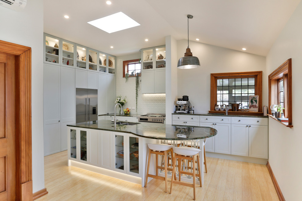 Photo of a large traditional l-shaped eat-in kitchen in Christchurch with an undermount sink, shaker cabinets, green cabinets, granite benchtops, green splashback, metal splashback, stainless steel appliances, bamboo floors, with island and green benchtop.