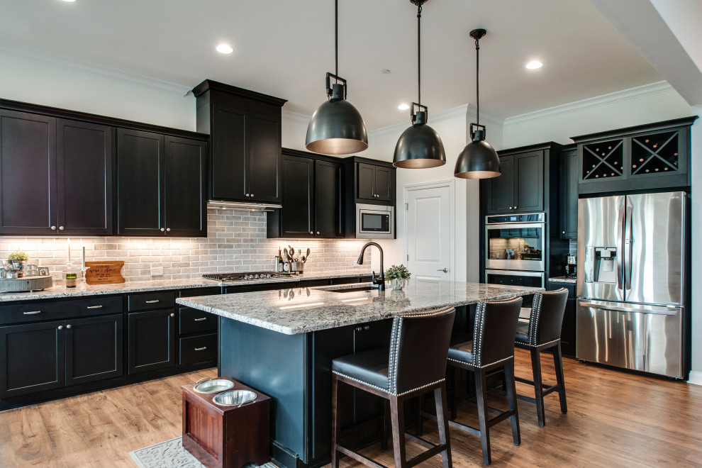 Design ideas for a mid-sized transitional eat-in kitchen in Nashville with an undermount sink, shaker cabinets, black cabinets, granite benchtops, grey splashback, limestone splashback, stainless steel appliances, medium hardwood floors, with island, brown floor and multi-coloured benchtop.