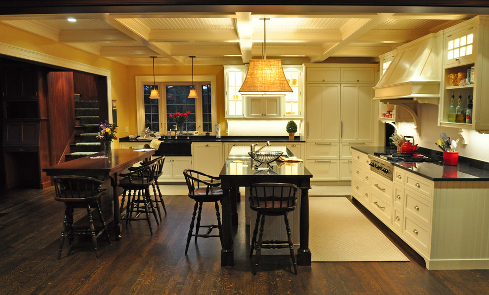 Inspiration for a large traditional l-shaped eat-in kitchen in Boston with shaker cabinets, white cabinets, dark hardwood floors, with island, a farmhouse sink and solid surface benchtops.