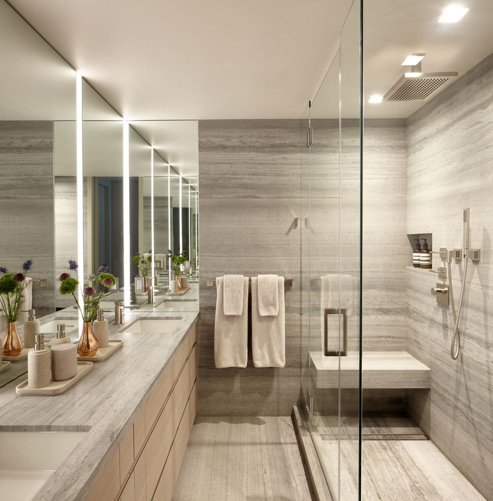 Mid-sized modern master bathroom in New York with flat-panel cabinets, light wood cabinets, a corner shower, a wall-mount toilet, gray tile, travertine, grey walls, travertine floors, an undermount sink, limestone benchtops, grey floor, a hinged shower door and grey benchtops.