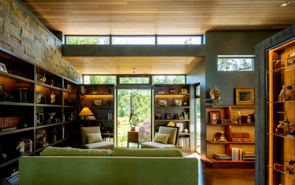 Inspiration for a mid-sized contemporary home office in Seattle with a library, grey walls, dark hardwood floors, a two-sided fireplace, a concrete fireplace surround, a built-in desk, brown floor, wood and panelled walls.