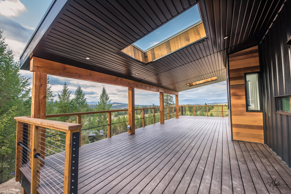 This is an example of an expansive industrial backyard deck in Vancouver with a roof extension.
